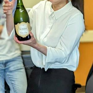 Jiaqi Ma holding champagne and smiling at PhD defense celebration