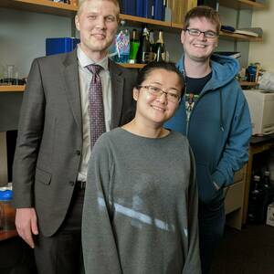 Three PhD students stand together and pose for photo in 2017